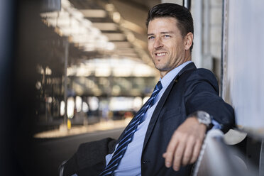 Smiling businessman waiting on station platform - DIGF06439