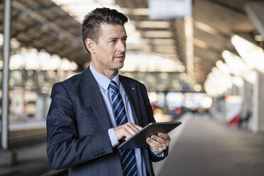 Businessman using tablet at train station - DIGF06440