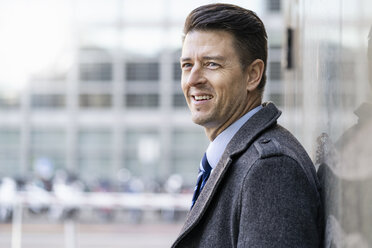 Portrait of smiling businessman at a wall - DIGF06467