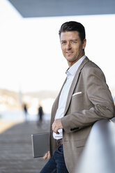 Lächelnder Geschäftsmann mit Tablet stehend im Freien - DIGF06481