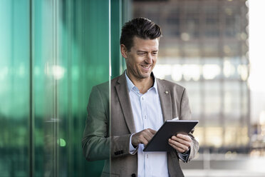 Smiling businessman using tablet outdoors - DIGF06484