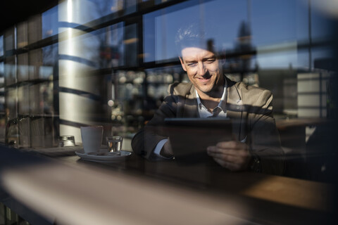 Businessman using tablet behind the window in a cafe stock photo