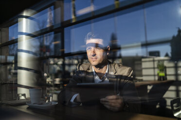 Businessman using tablet behind the window in a cafe - DIGF06501