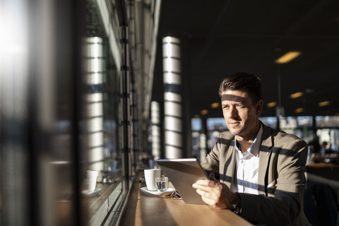 Businessman using tablet at the window in a cafe stock photo