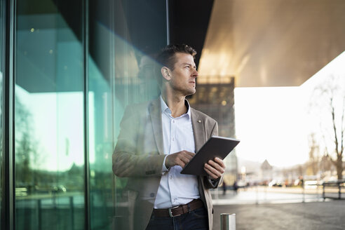 Businessman using tablet outside a building in the city - DIGF06507