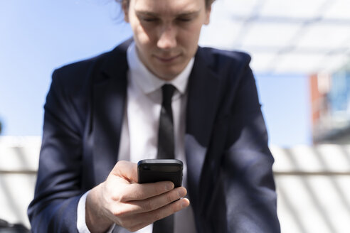 Italien, Florenz, junger Geschäftsmann mit Smartphone im Freien - FMOF00503