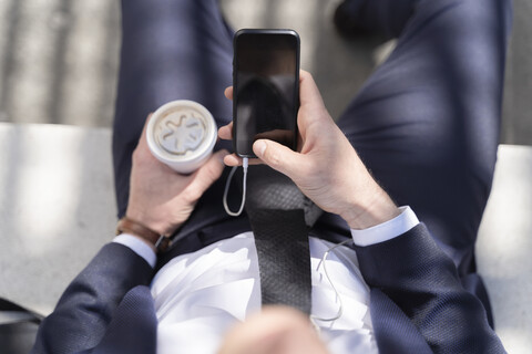 Nahaufnahme eines Geschäftsmannes mit Kaffee zum Mitnehmen und Smartphone im Freien, lizenzfreies Stockfoto