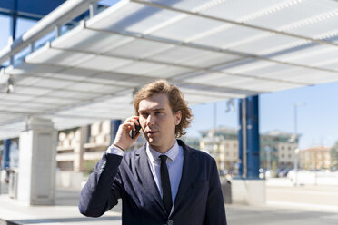Italien, Florenz, junger Geschäftsmann auf Smartphone im Freien - FMOF00524
