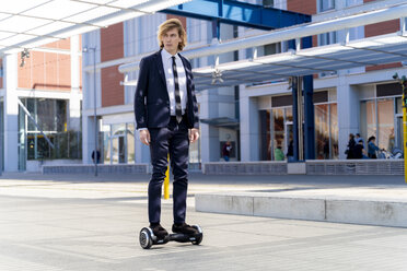 Italien, Florenz, junger Geschäftsmann fährt Hoverboard in der Stadt - FMOF00535