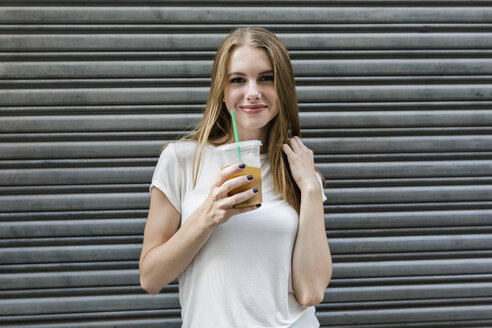 Junge Frau in der Stadt trinkt Kaffee zum Mitnehmen - GIOF06039