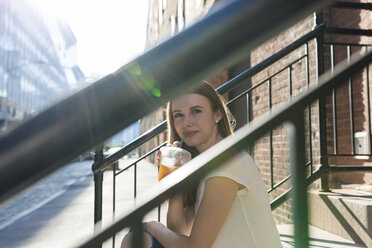 Junge Frau erkundet New York City, sitzt auf einer Treppe und trinkt Kaffee - GIOF06042