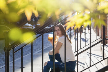 Young woman exploring New York City, sitting on stairs, drinking coffee - GIOF06043