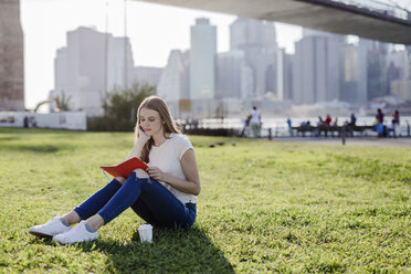 Young woman exploring New York City, taking a break, reading book - GIOF06065