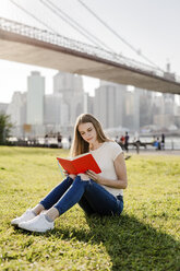 Young woman exploring New York City, taking a break, reading book - GIOF06067