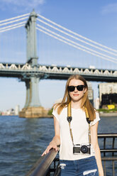 Junge Frau erkundet New York City, steht mit Kamera an der Brooklyn Bridge - GIOF06076