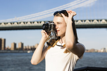 Young woman exploring New York City, taking pictures at Brooklyn Bridge - GIOF06077