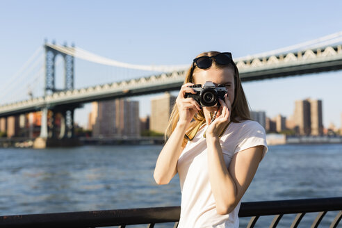Junge Frau, die New York City erkundet und Fotos an der Brooklyn Bridge macht - GIOF06078