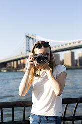 Junge Frau, die New York City erkundet und Fotos an der Brooklyn Bridge macht - GIOF06079