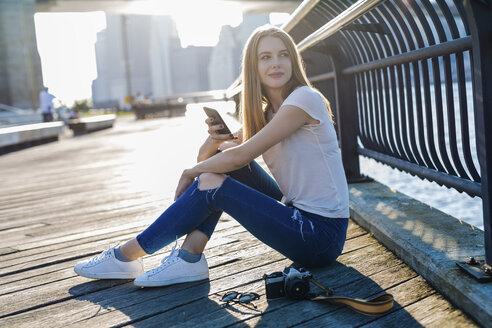 Junge Frau erkundet New York City, macht eine Pause und benutzt ihr Smartphone - GIOF06084