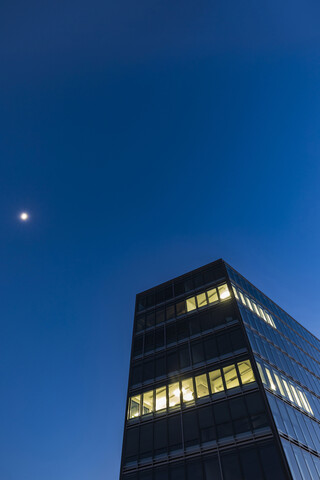 Deutschland, Stuttgart, beleuchtete Fenster an modernem Bürogebäude zur blauen Stunde, lizenzfreies Stockfoto