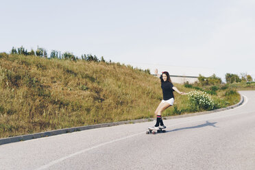 Spain, teenage girl riding skateboard down a road - ERRF00846