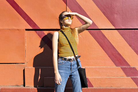 Teenager-Mädchen an einer Mauer, das den Sonnenschein genießt, lizenzfreies Stockfoto