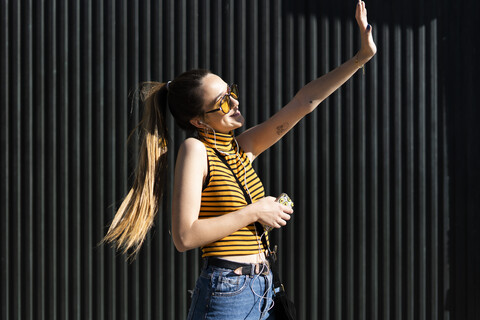 Glückliches Teenager-Mädchen mit Kopfhörern und Smartphone genießt den Sonnenschein, lizenzfreies Stockfoto
