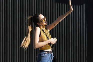 Happy teenage girl with earphones and smartphone enjoying the sunshine - ERRF00856