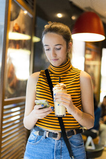 Spanien, junges Mädchen mit Milchshake und Smartphone - ERRF00871