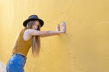 Portrait of teenage girl wearing hat at yellow wall - ERRF00885