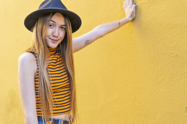 Portrait of teenage girl wearing hat at yellow wall - ERRF00887