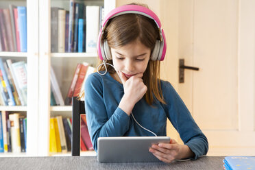Kleines Mädchen macht Hausaufgaben mit Kopfhörern und digitalem Tablet - LVF07945