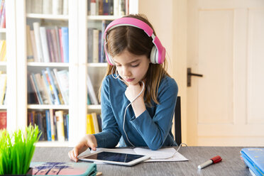 Kleines Mädchen macht Hausaufgaben mit Kopfhörern und digitalem Tablet - LVF07946