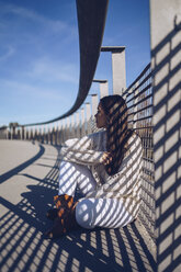 Junge Frau auf einer Brücke sitzend - RSGF00167