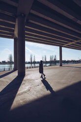 Young woman walking at an underpass at a lake - RSGF00172