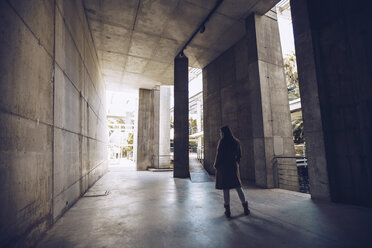 Rear view of young woman standing at an underpass - RSGF00181