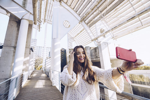 Glückliche junge Frau macht ein Selfie auf einer Brücke - RSGF00185