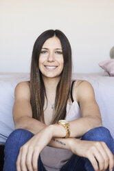 Portrait of smiling young woman with long brown hair at home - IGGF00933