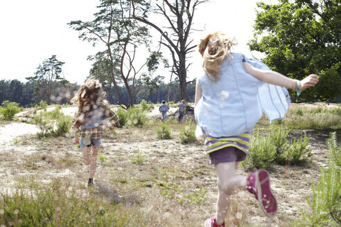 Rückansicht von zwei Mädchen, die durch eine Dünenlandschaft laufen - AMEF00051