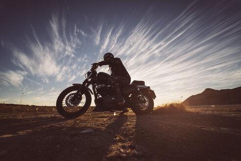 Mann auf Motorrad in der Natur bei Sonnenuntergang - OCMF00357