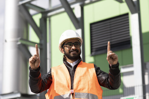 Porträt eines Bauingenieurs vor einem Kraftwerk mit Schutzhelm und Sicherheitsweste - SGF02343