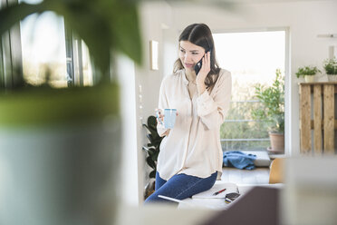 Junge Frau telefoniert zu Hause mit einem Handy - UUF16954