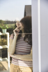 Portrait of pensive young woman behind windowpane - UUF17028