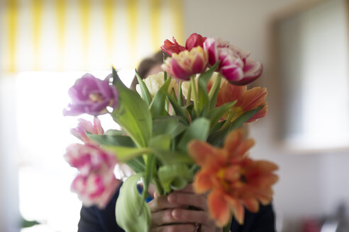 Frau versteckt sich hinter einem Tulpenstrauß - SGF02348