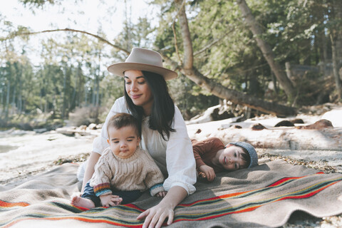 Mother and sons lying on blanket on the beach stock photo