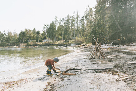 Boy playing on a the beach, building a drift wood fort stock photo