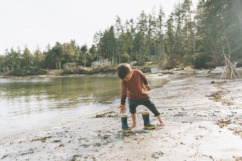 Junge spielt am Strand, läuft barfuß im Schlamm, lizenzfreies Stockfoto