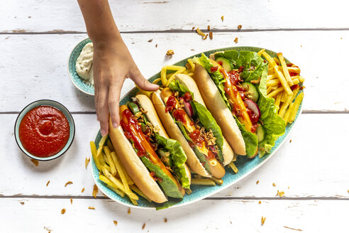Hot Dogs mit Pommes frites, Ketchup und Mayonnaise, Hot Dog in die Hand nehmen - SARF04211