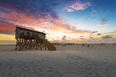 Germany, Sankt Peter Ording, pile dwellings on the beach in sunset - MKFF00476