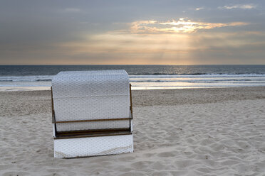 Deutschland, Sylt, Nordsee, Sandstrand mit überdachtem Strandkorb im Sonnenuntergang - MKFF00488